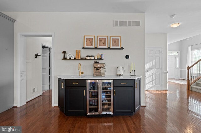 indoor wet bar featuring beverage cooler, dark wood-style flooring, stairs, and baseboards