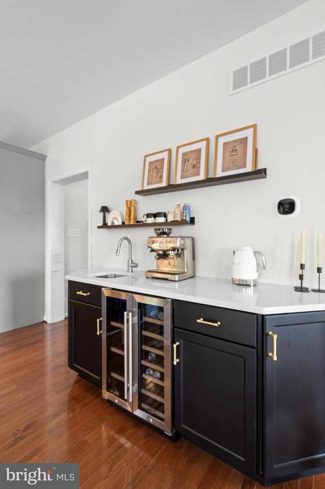 indoor wet bar with dark wood-style flooring and beverage cooler