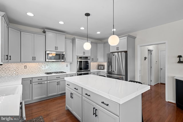 kitchen featuring stainless steel appliances, gray cabinetry, tasteful backsplash, dark wood-type flooring, and recessed lighting