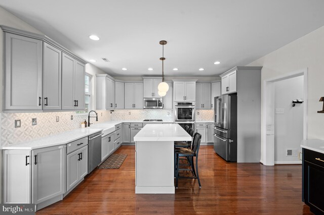 kitchen featuring stainless steel appliances, a sink, a breakfast bar, a center island, and backsplash