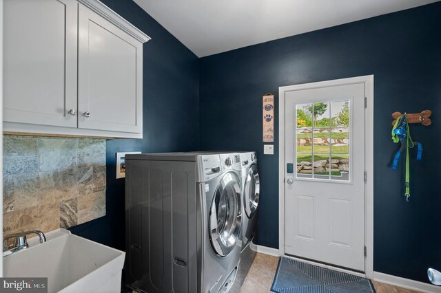 washroom featuring cabinet space, washer and dryer, baseboards, and light tile patterned flooring