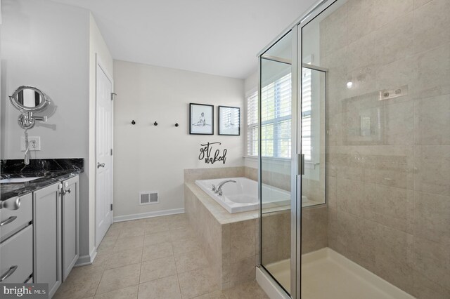 full bath with a stall shower, tile patterned floors, a garden tub, vanity, and baseboards