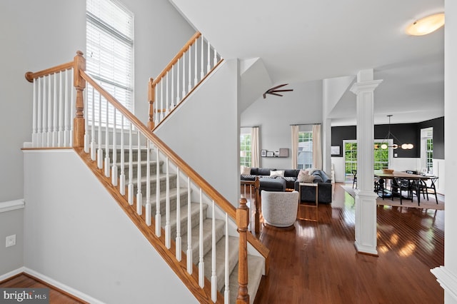 stairway with decorative columns, wood finished floors, a ceiling fan, and baseboards