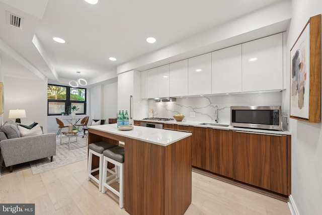 1427 Rhode Island Ave NW Unit L01, Washington, DC 20005 - kitchen featuring stainless steel microwave, a sink, modern cabinets, light wood finished floors, and light countertops