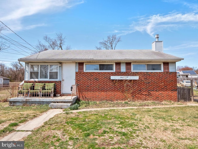 view of front of property with a chimney, brick siding, and roof with shingles