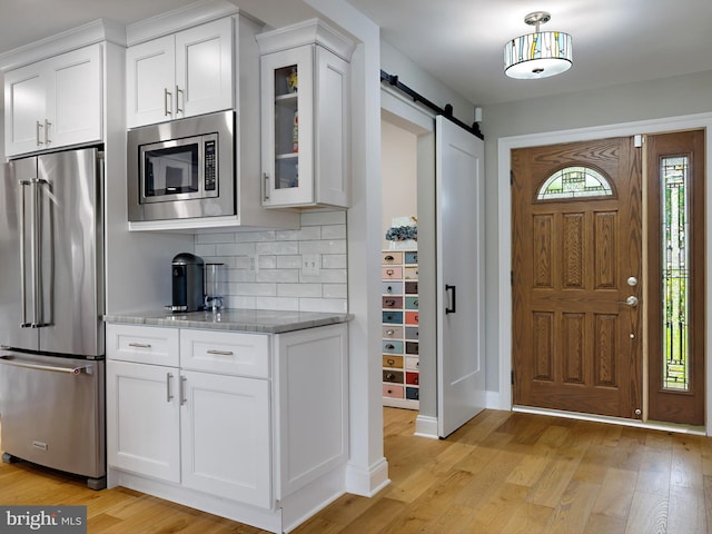 foyer with a barn door, light wood-type flooring, and baseboards
