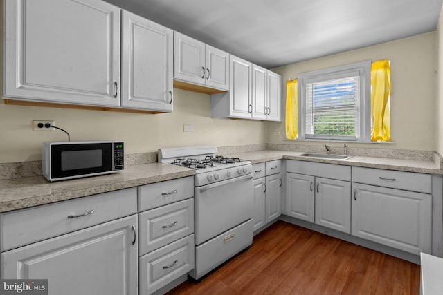 kitchen with white range with gas cooktop, black microwave, a sink, white cabinets, and dark wood finished floors