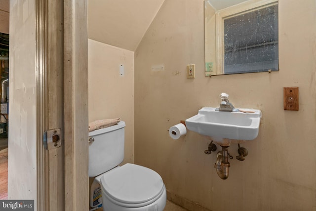 half bathroom with toilet, lofted ceiling, and a sink