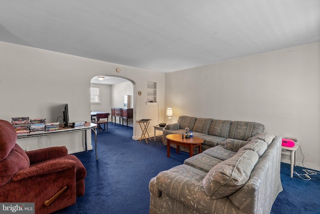 carpeted living area featuring arched walkways and baseboards