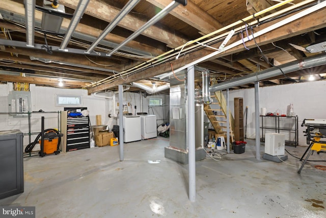 basement with washing machine and dryer, electric panel, heating unit, and stairway
