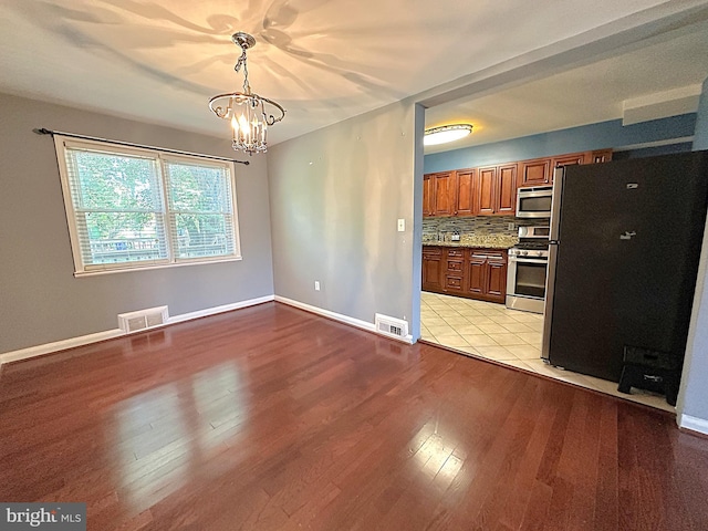 1206 Cedarcroft Rd, Baltimore, MD 21239 - kitchen featuring appliances with stainless steel finishes, a chandelier, brown cabinetry, light wood-type flooring, and decorative light fixtures