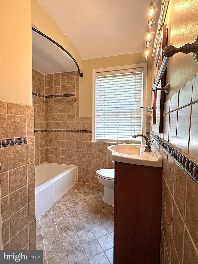 1206 Cedarcroft Rd, Baltimore, MD 21239 - bathroom featuring tile walls, vanity, toilet, washtub / shower combination, and a wainscoted wall