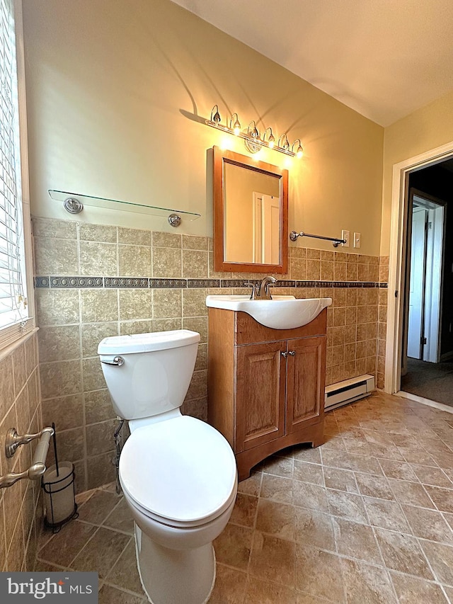 1206 Cedarcroft Rd, Baltimore, MD 21239 - bathroom featuring tile walls, a baseboard radiator, vanity, toilet, and a wainscoted wall