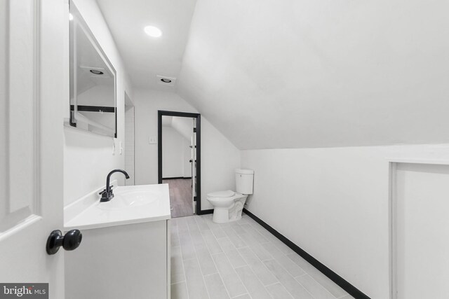 bathroom featuring vaulted ceiling, vanity, toilet, recessed lighting, and baseboards