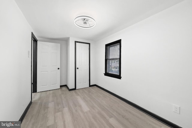 unfurnished bedroom with light wood-style flooring and baseboards