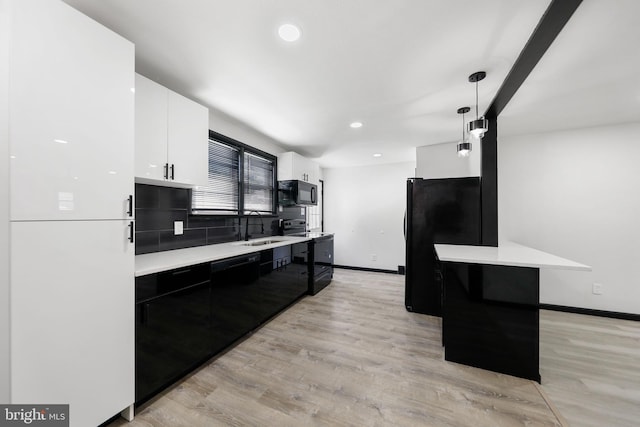 kitchen with black appliances, a sink, light countertops, white cabinets, and baseboards