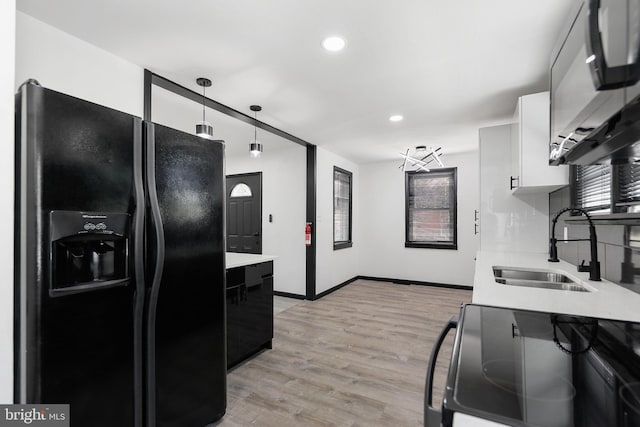 kitchen featuring black refrigerator with ice dispenser, a sink, range with electric cooktop, light countertops, and recessed lighting