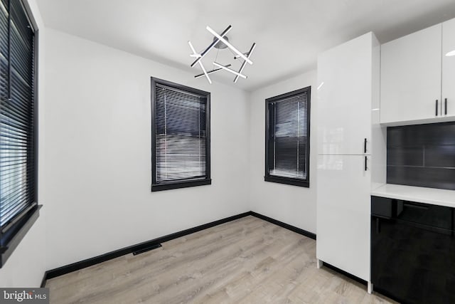 unfurnished dining area with light wood-style floors and baseboards
