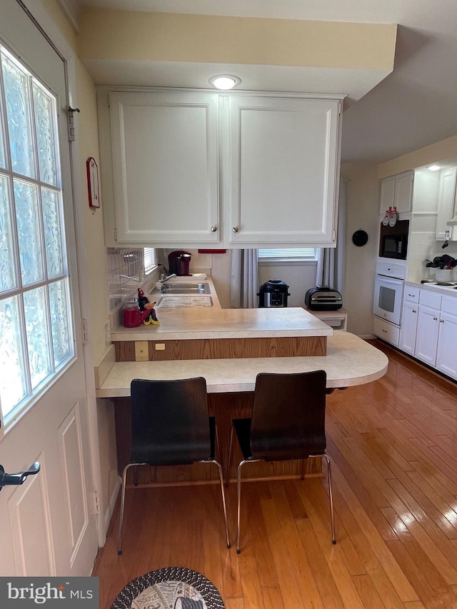 99 Exeter Ct, Shepherdstown, WV 25443 - kitchen with oven, a sink, white cabinets, light countertops, and backsplash