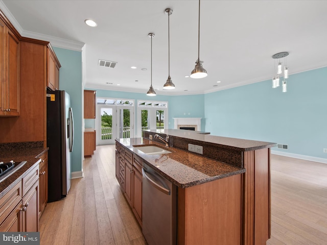 27173 Barefoot Blvd Unit 15, Millsboro, DE 19966 - kitchen featuring stainless steel appliances, a sink, brown cabinetry, an island with sink, and light wood finished floors
