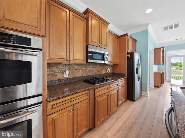 27173 Barefoot Blvd Unit 15, Millsboro, DE 19966 - kitchen with stainless steel appliances, brown cabinets, light wood-style flooring, ornamental molding, and backsplash