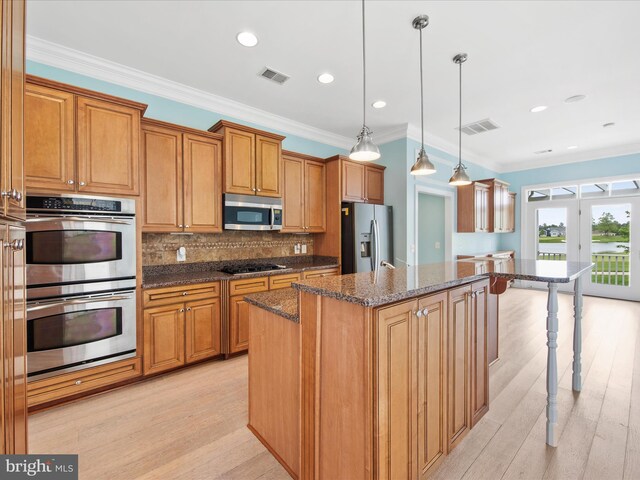 27173 Barefoot Blvd Unit 15, Millsboro, DE 19966 - kitchen with appliances with stainless steel finishes, a kitchen island, brown cabinets, dark stone counters, and decorative backsplash