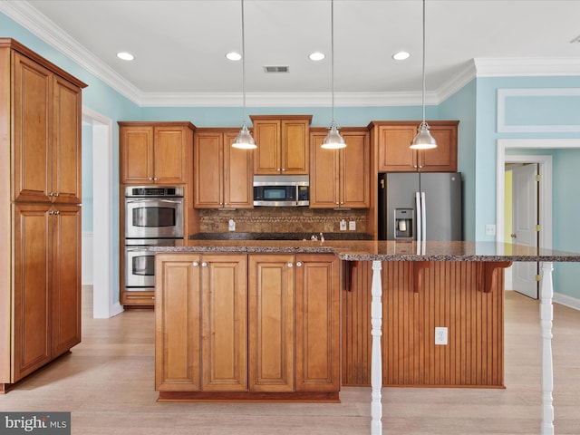27173 Barefoot Blvd Unit 15, Millsboro, DE 19966 - kitchen with stainless steel appliances, brown cabinetry, light wood-type flooring, a breakfast bar area, and backsplash