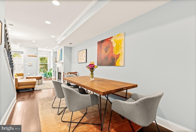dining room featuring recessed lighting, light wood finished floors, baseboards, a fireplace, and ornamental molding