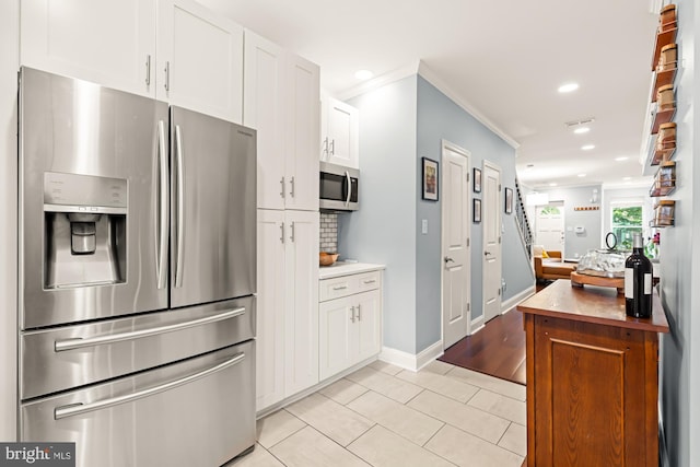 kitchen with appliances with stainless steel finishes, crown molding, white cabinets, light tile patterned floors, and recessed lighting
