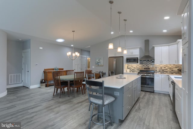 82 S Village Cir Unit 238, Palmyra, PA 17078 - kitchen with stainless steel appliances, wall chimney exhaust hood, lofted ceiling, a kitchen island, and tasteful backsplash