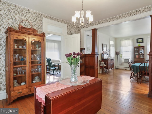 214 Center St, Edinburg, VA 22824 - dining room featuring decorative columns, wood-type flooring, wallpapered walls, a chandelier, and a baseboard radiator