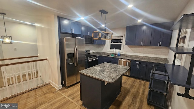 kitchen featuring stainless steel appliances, a sink, dark stone counters, tasteful backsplash, and wood finished floors