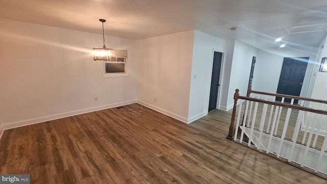 spare room with baseboards and wood finished floors