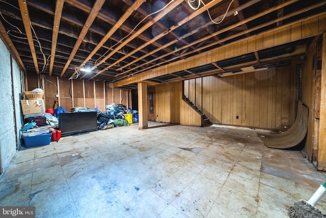 unfinished below grade area featuring stairs, tile patterned floors, and wood walls