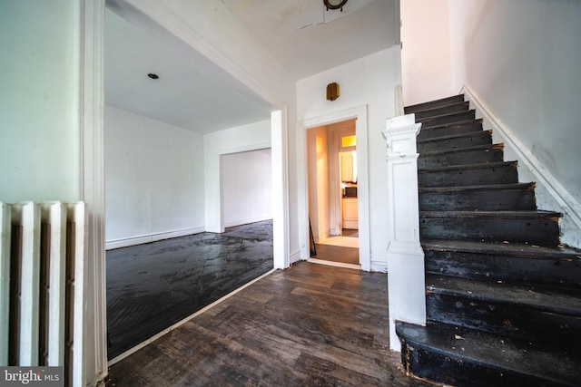 stairway featuring radiator, wood finished floors, and baseboards