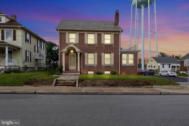 multi unit property with brick siding, a chimney, and a yard