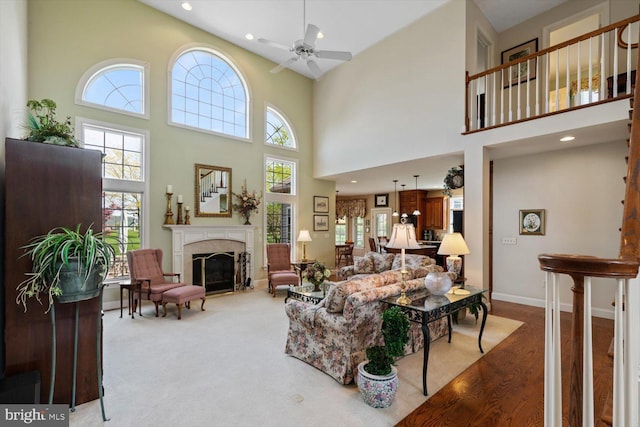 living area with plenty of natural light, a glass covered fireplace, a high ceiling, a ceiling fan, and recessed lighting