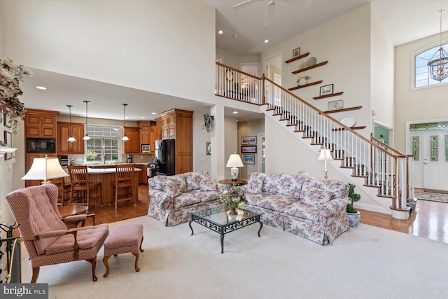 living area featuring a high ceiling, stairway, recessed lighting, a ceiling fan, and wood finished floors