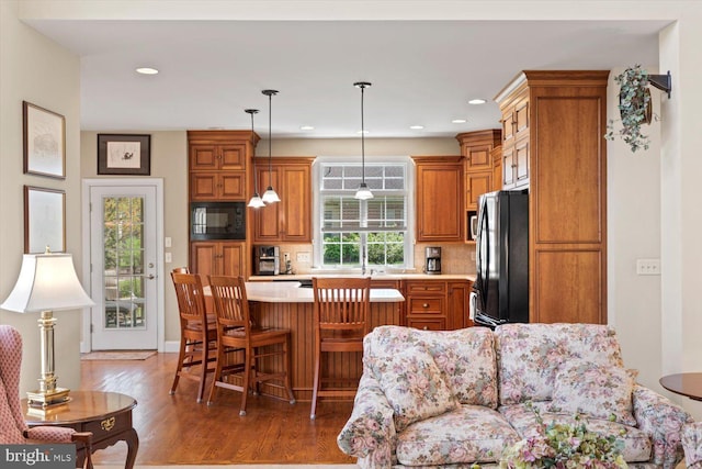 kitchen featuring black appliances, light countertops, wood finished floors, brown cabinets, and a kitchen island