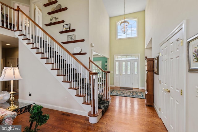entryway featuring a high ceiling, healthy amount of natural light, wood finished floors, baseboards, and stairs