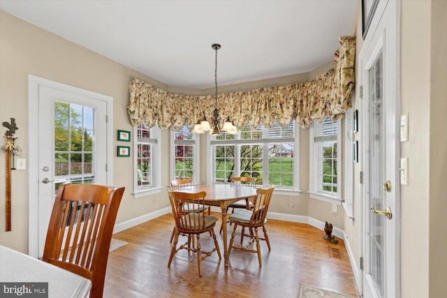 dining space with a chandelier, baseboards, and light wood-type flooring