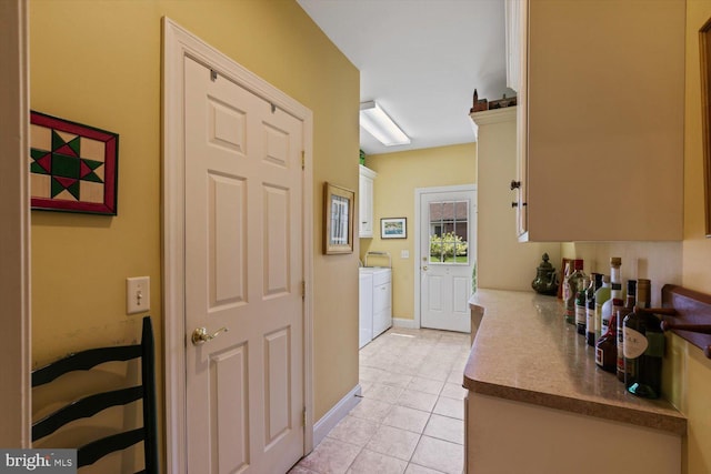hall with washing machine and dryer, light tile patterned floors, and baseboards