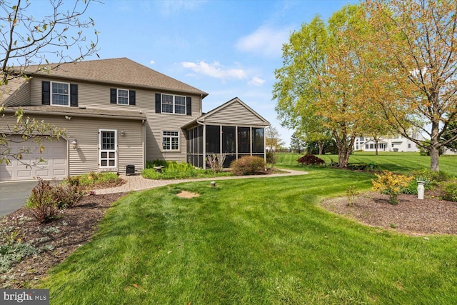 rear view of property featuring a sunroom, a lawn, and asphalt driveway