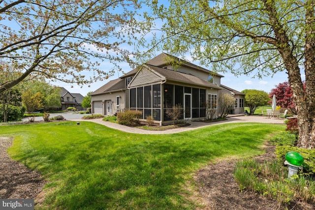rear view of house featuring a sunroom, a lawn, and a garage
