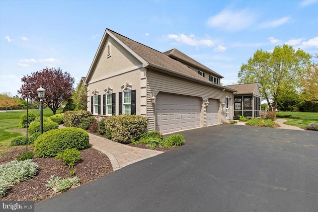 view of home's exterior with an attached garage, asphalt driveway, stucco siding, and a shingled roof
