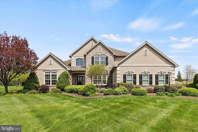 traditional home featuring stone siding, stucco siding, and a front yard
