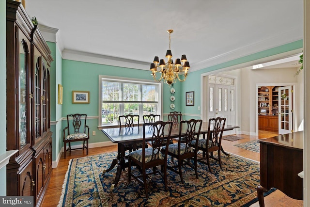 dining area featuring a chandelier, wood finished floors, crown molding, and baseboards