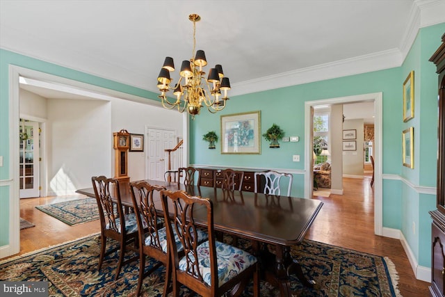 dining room featuring a chandelier, wood finished floors, ornamental molding, and baseboards