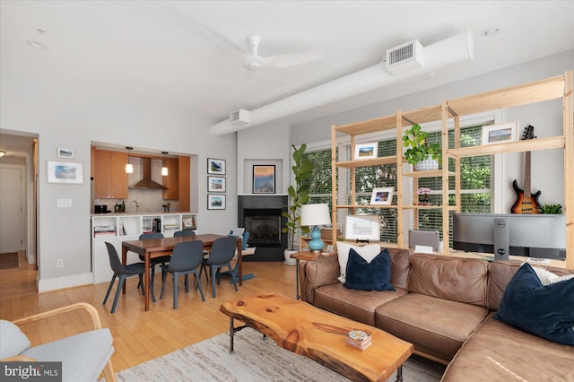 living room with light wood finished floors, a fireplace with raised hearth, and healthy amount of natural light
