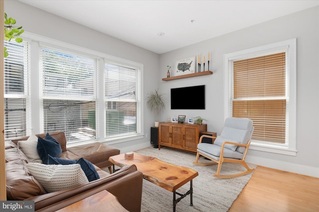 living room featuring healthy amount of natural light, baseboards, and light wood finished floors